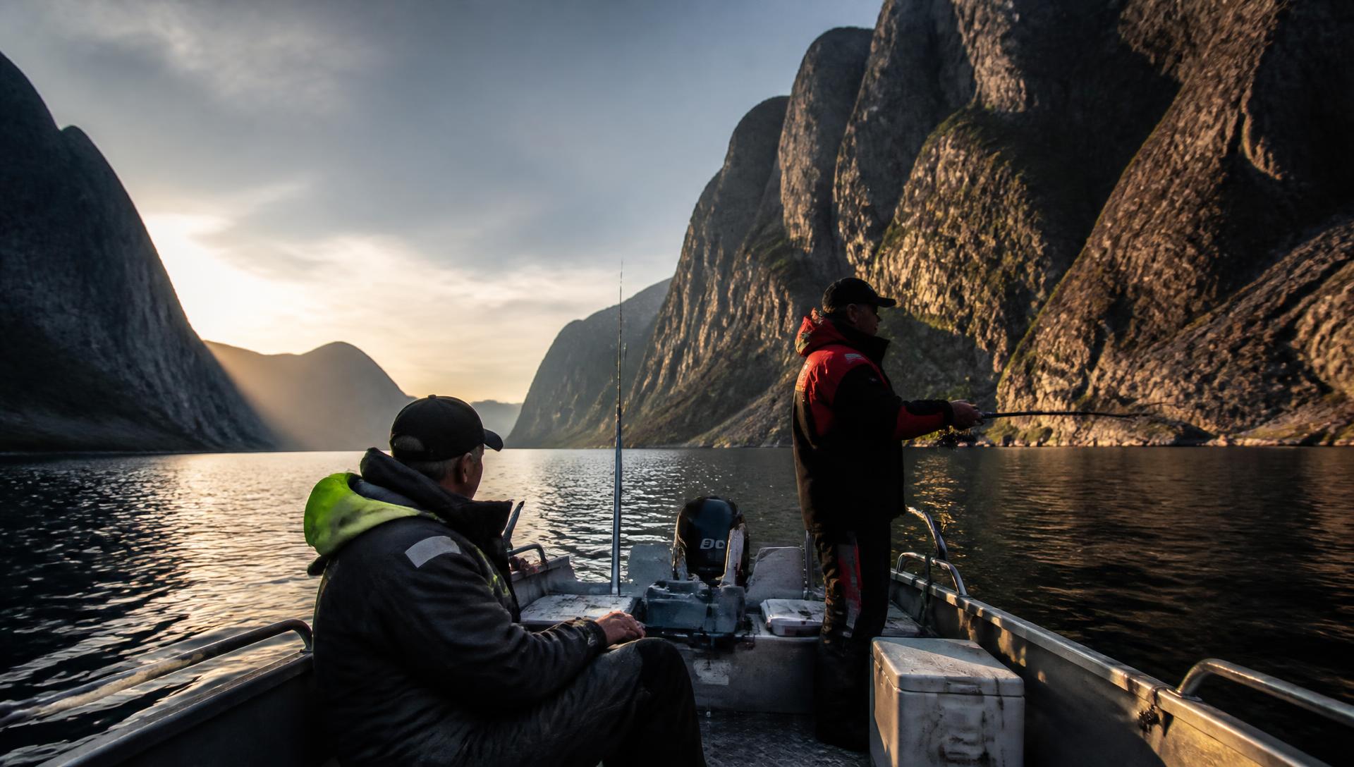 Norvegijos fjordas auksinės valandos šviesoje su žvejybos valtimi